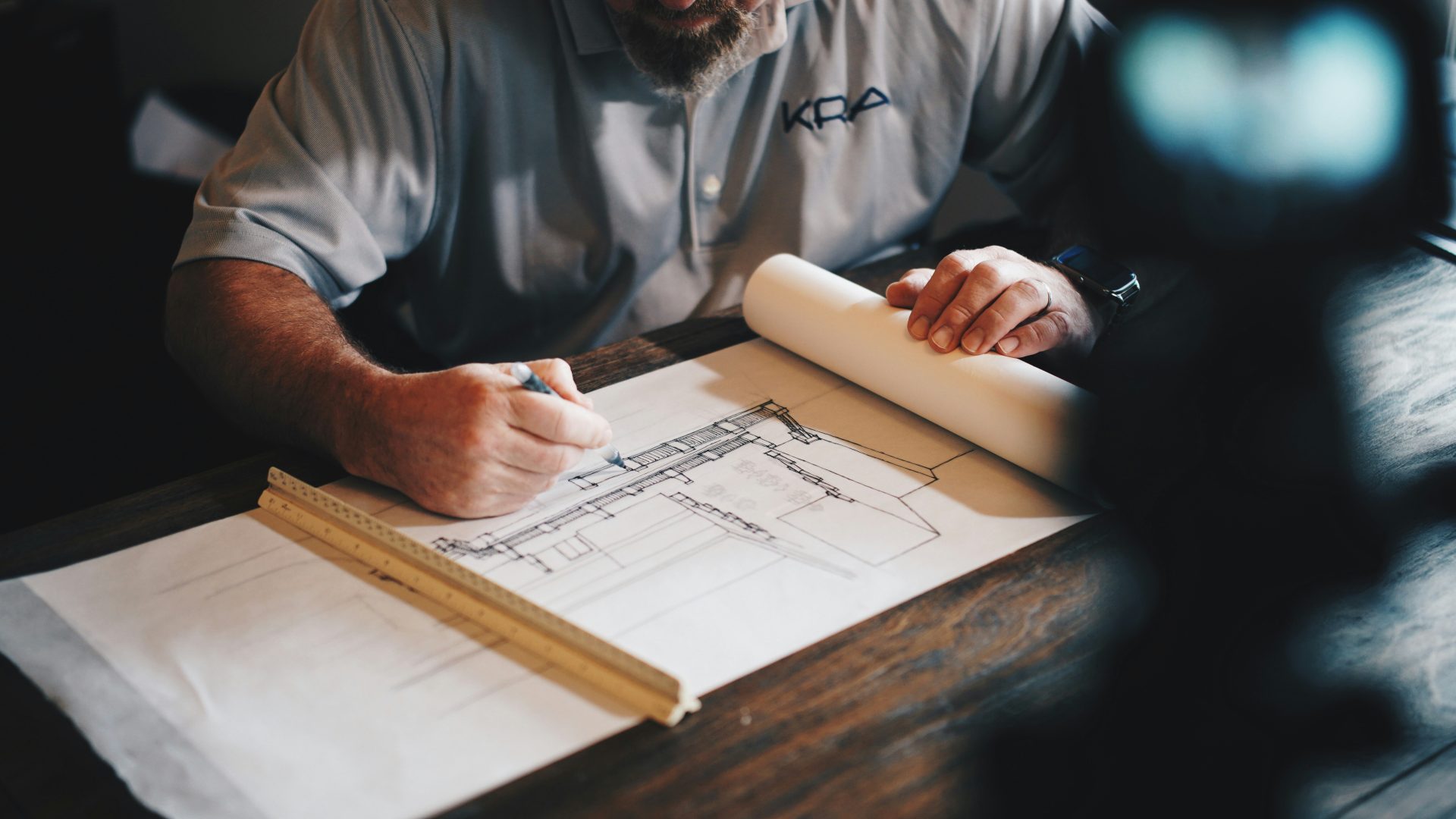 Un arquitecto trabajando en un borrador con lápiz y regla.
